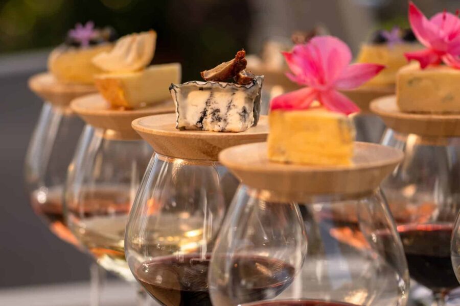 Assorted gourmet cheeses with edible flowers served on wooden pegs at Palm House Boutique Hotel and Spa, perfect for a luxury wine and dine experience.