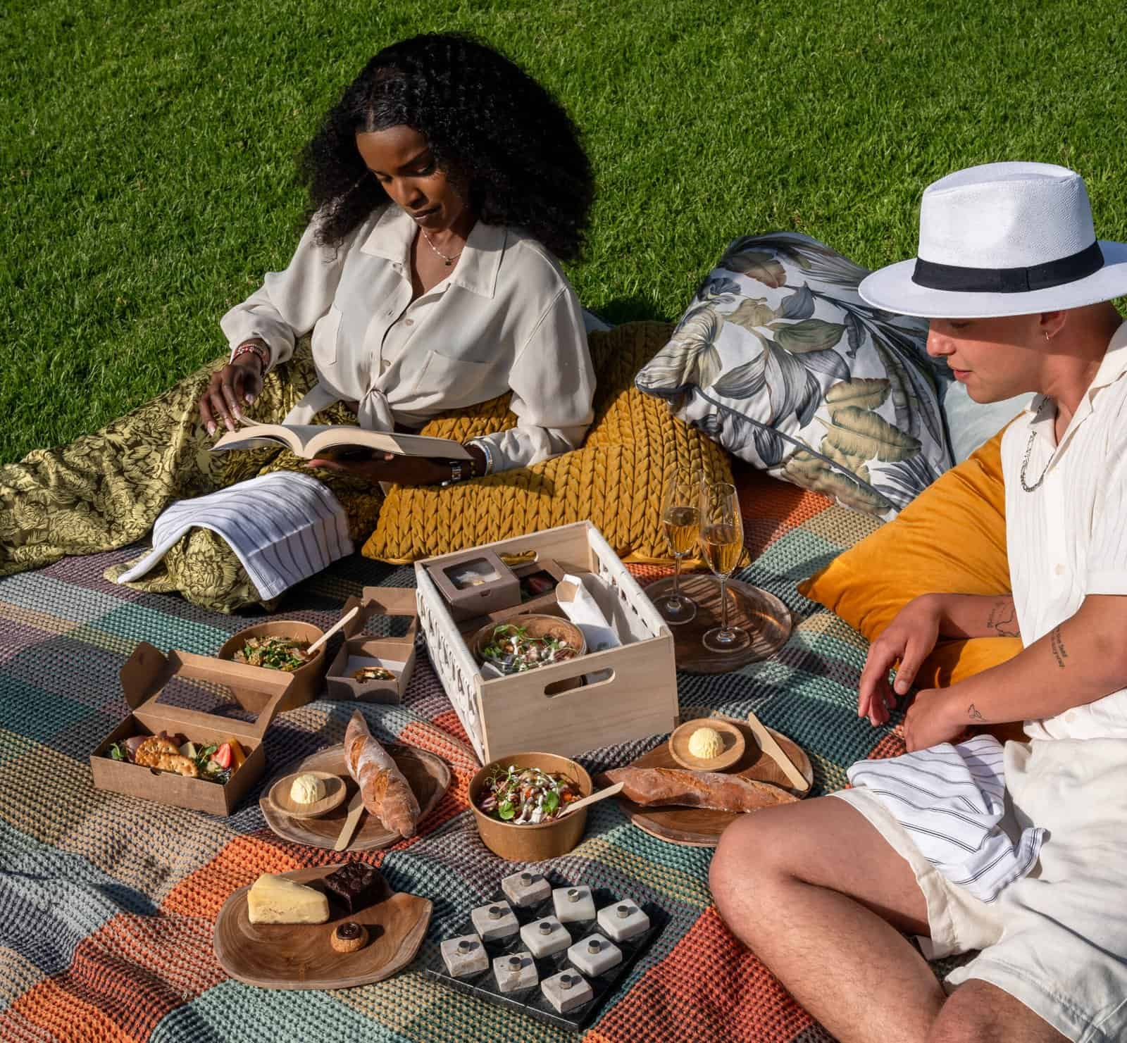 Relaxing outdoor picnic at Palm House Boutique Hotel and Spa, featuring gourmet food, refreshing drinks, and comfortable cushions amidst lush greenery. Perfect for a luxurious spa escape.
