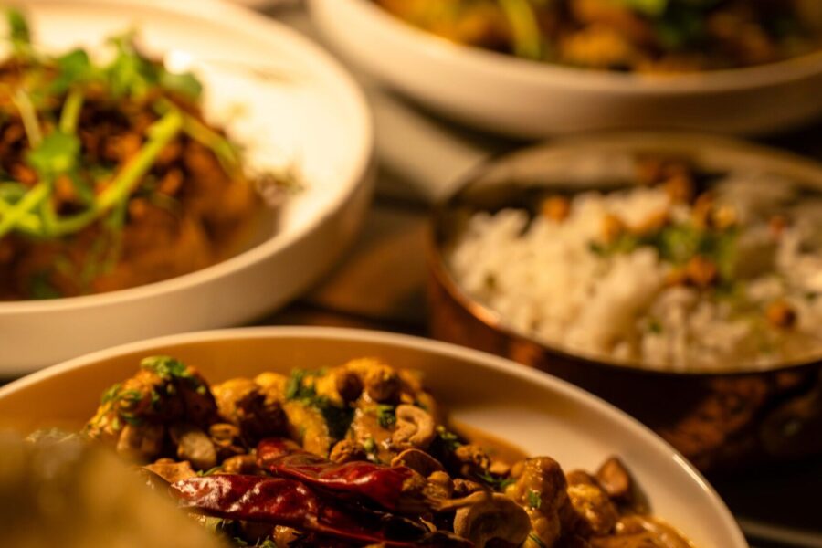 A vibrant display of traditional Indian dishes served in white bowls, showcasing rich spices, fresh herbs, and colorful ingredients, perfect for the Spice Route culinary experience.