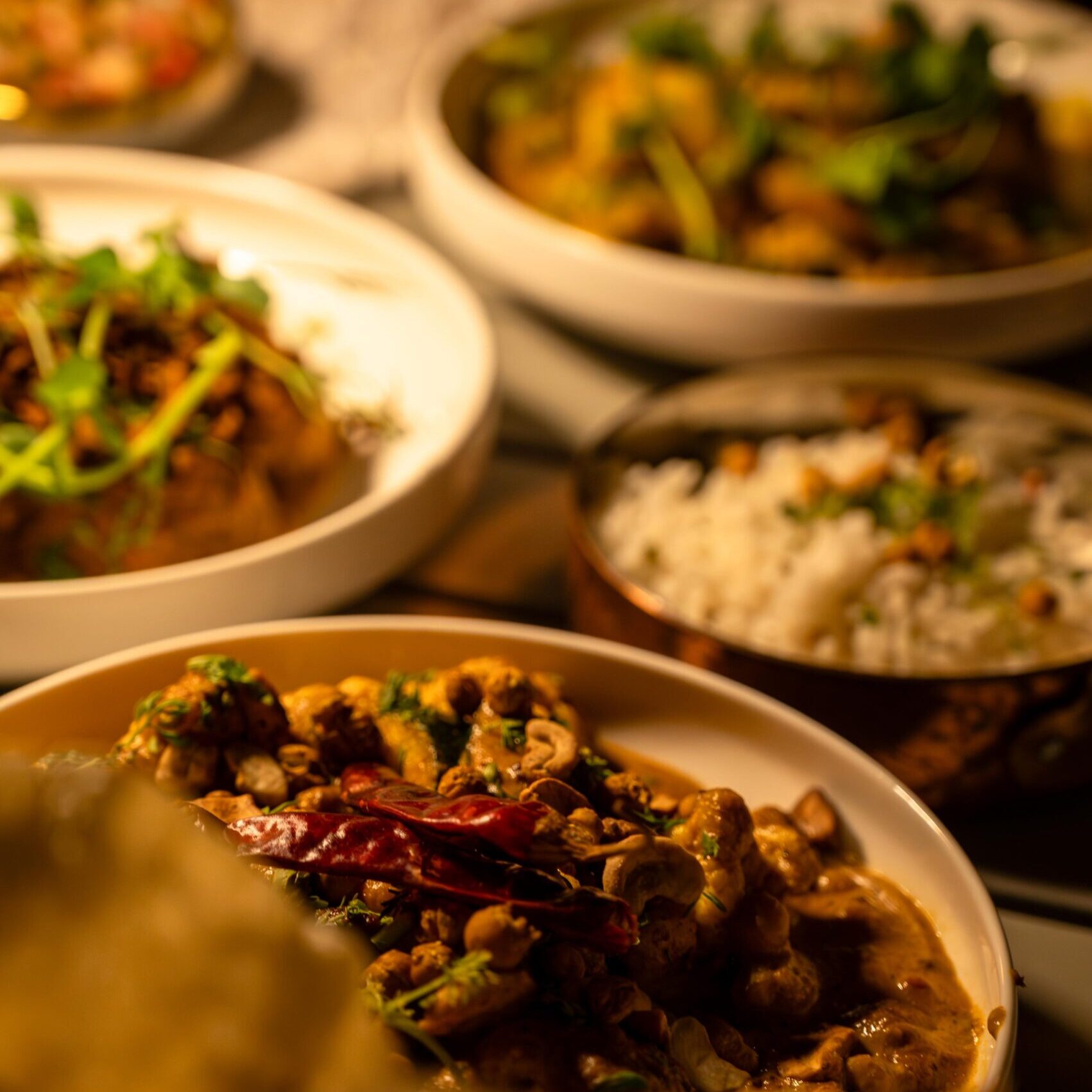A vibrant display of traditional Indian dishes served in white bowls, showcasing rich spices, fresh herbs, and colorful ingredients, perfect for the Spice Route culinary experience.