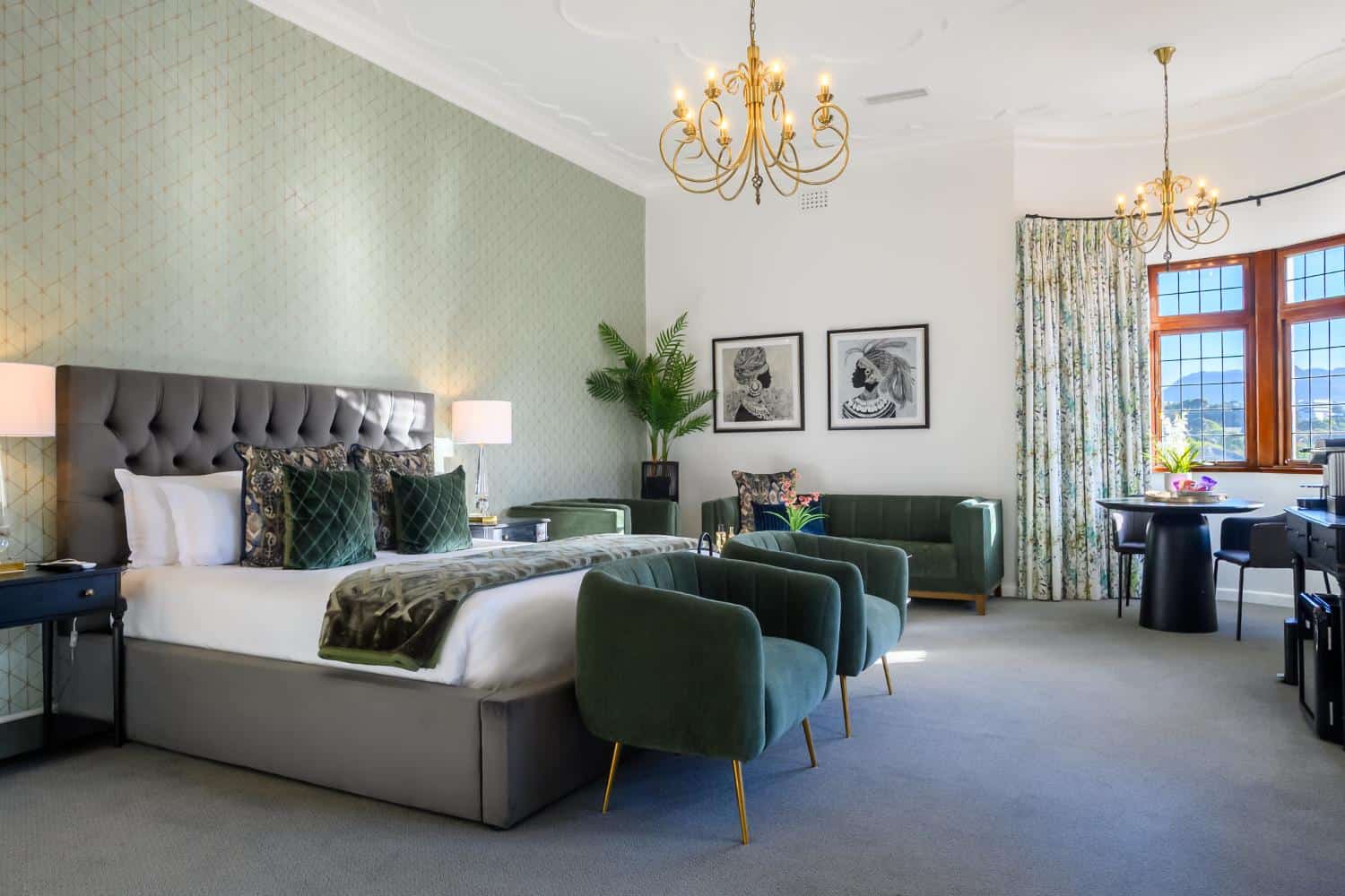 Luxurious hotel bedroom with a plush bed, elegant green armchairs, and stylish decor at Palm House Boutique Hotel and Spa, offering a relaxing and sophisticated stay in South Africa.